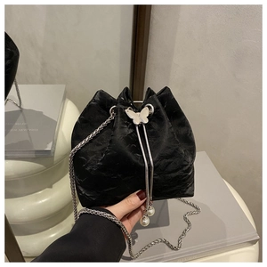 Detail of black velvet bucket bag with silver butterfly buckle and pearl charms