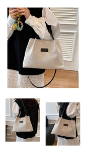 Detail view of large beige woven tote bag with black straps and fashion logo patch
