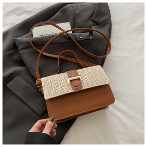 Detail of woven fabric flap and brown leather crossbody bag with gold buckle hardware