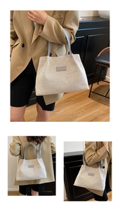 Close-up of beige canvas tote bag with grey fashion label and leather handle detail
