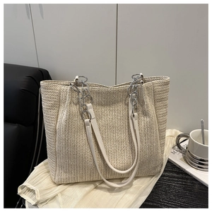 Detail of V-shaped straw weave pattern and metal chain strap on beige tote bag