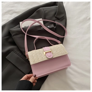 Close-up of pink leather crossbody bag with woven straw flap and gold metal buckle