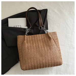 Detail of herringbone woven tote bag with brown leather strap and silver metal rings