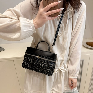 Sac bandoulière en tweed noir avec détails en cuir porté par un mannequin en intérieur