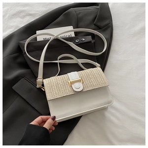 Detail of woven straw and white leather crossbody bag with a gold rectangular metal clasp