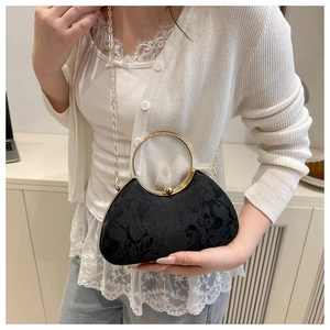 Detail of black crescent handbag with floral jacquard texture and golden ring handle