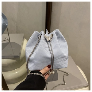 Detail of light blue bucket bag with pleated texture, silver butterfly and pearl charms