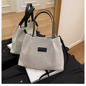 Detail of canvas tote bag with black leather handles and printed fashion logo tag