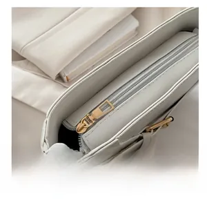 Close-up of smooth gold zipper on a creamy white leather handbag for women