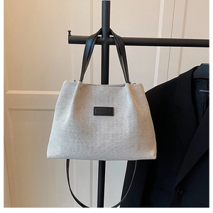 Macro shot of grey woven texture tote bag with black leather strap and Fashion label