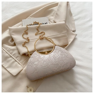 Detail of floral embroidery on a satin evening clutch with a gold circular handle