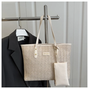 Detailed V-shaped woven texture on beige straw tote bag with metal logo and long handles