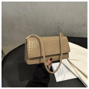 Close-up of beige woven texture shoulder bag with gold metal hardware and slim handle