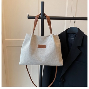 Detail view of large canvas tote bag with brown leather straps and fashion patch