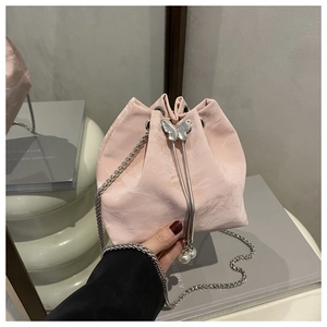 Detailed view of pink drawstring bucket bag with silver chain and pearl butterfly clasp