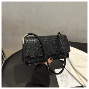 Close-up of black woven leather texture and gold buckle on a stylish baguette bag