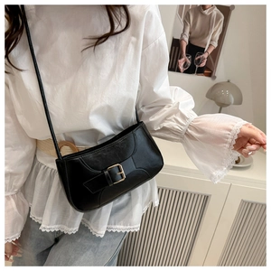 Detail of vintage black leather crossbody bag with golden square buckle and thin strap