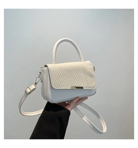 Detailed view of white faux leather handbag featuring beige woven texture and gold accent
