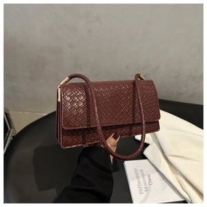 Close-up of burgundy woven leather texture and gold hardware on a shoulder bag