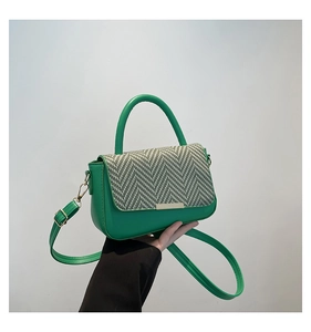Detail of green leather handbag featuring a textured green and white tweed flap cover