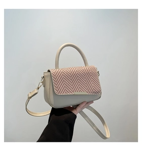 Detail of elegant cream leather handbag with houndstooth fabric flap and gold hardware