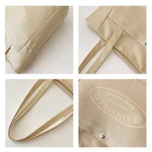 Detail view of large canvas tote bag showing metal snap button, logo print and stitching