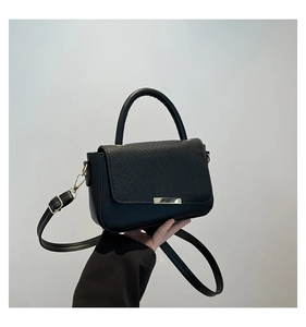 Close-up of black leather crossbody bag with snake texture flap and gold metal buckle