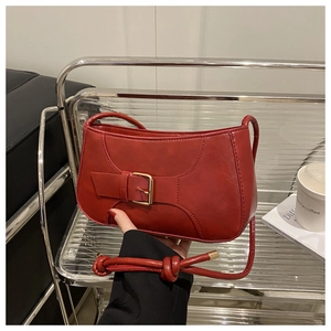 Detail of red crescent shoulder bag with golden buckle and stylish knotted strap