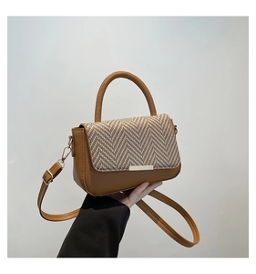 Detail view of the brown leather and tweed patchwork textured shoulder bag with gold hardware