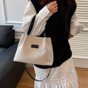 Minimalist cream canvas tote bag with black leather handles and shoulder straps