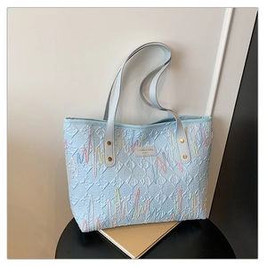 Détail du cabas bleu clair avec motif E gaufré et broderie ondulée multicolore