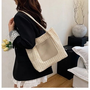 Detail of woven straw shoulder bag with contrast leather pocket and fashion text