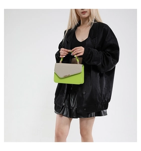Detail of neon green leather handbag with beige textured woven flap and metal bar trim