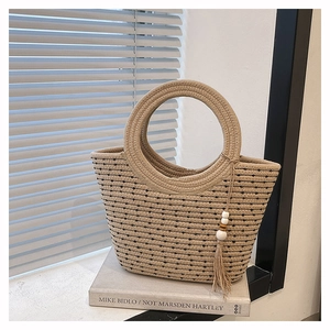 Détail d'un sac à main en paille tressée avec motifs noirs et décoration de pompon blanc
