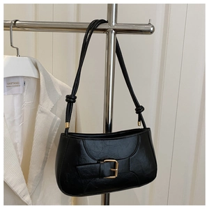 Detail of vintage black glossy underarm bag featuring golden buckle and knotted double straps