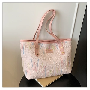 Détail du sac cabas rose avec surpiqûres ondulées colorées et logo en métal doré