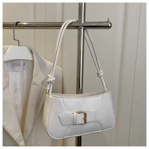 Detail of white shoulder bag featuring gold square buckle and decorative knotted strap