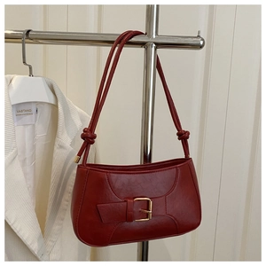Detail view of red baguette bag featuring golden buckle and knotted shoulder strap detail