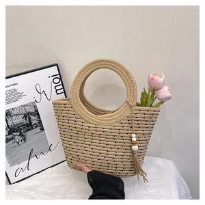 Détail du sac cabas en paille à pois noirs avec anses rondes et glands perlés