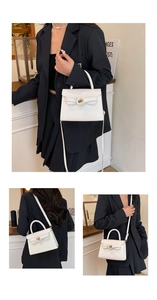 Detailed view of white leather handbag featuring a secure metallic twist-lock closure