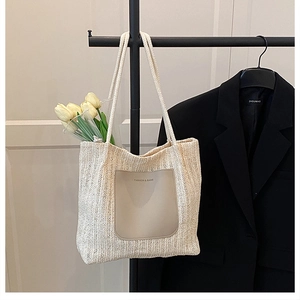 Close-up of beige woven tote bag with brown leather pocket and fashion branding