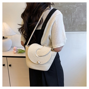 Détail de texture tressée sur sac à bandoulière crème avec grand fermoir en perle