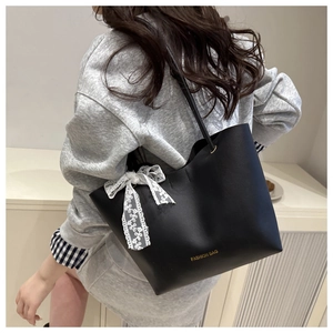 Détail du sac cabas en cuir noir avec nœud en dentelle blanche et texte de mode