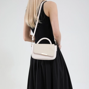 Minimalist beige crossbody handbag with woven texture shown on a black dress model