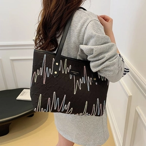 Grand sac cabas noir avec broderie colorée et bandoulières en cuir porté par un mannequin