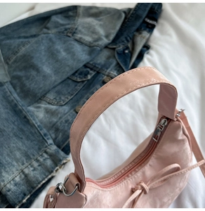 Close-up of pink leather dumpling bag with wide handle and knot details on denim