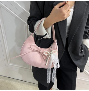 Vue détaillée du sac croissant rose avec nœud en dentelle et pendentif en perles