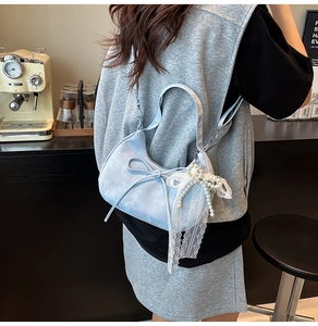 Détail du sac hobo en daim bleu clair avec franges en dentelle et perles et un nœud