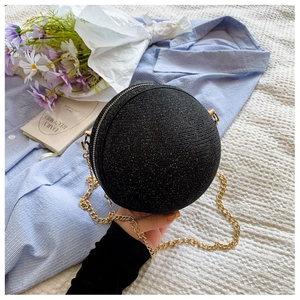 Macro shot of a black glitter sphere evening bag with a gold metal chain strap