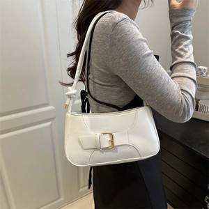 White faux leather baguette bag with gold buckle and knotted strap worn by a model